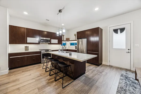 a kitchen with stainless steel appliances granite countertop a refrigerator a sink dishwasher a stove with wooden cabinets and floor