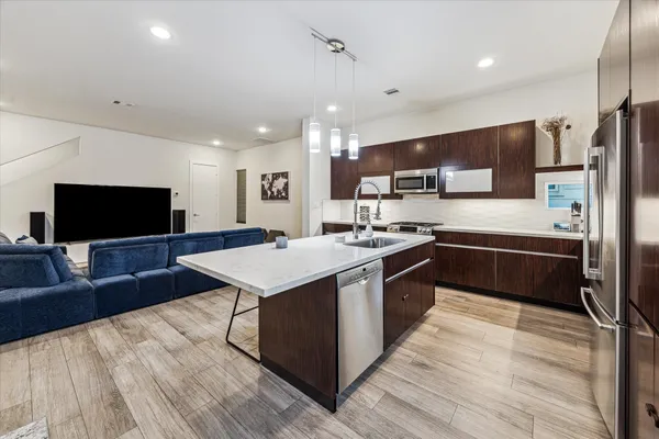 a large kitchen with stainless steel appliances a stove a sink dishwasher a refrigerator and a oven with wooden floor