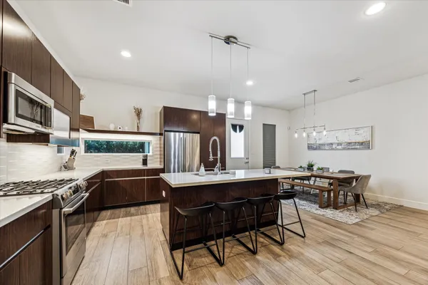 a view of a kitchen with kitchen island a dining table chairs wooden floor and a window