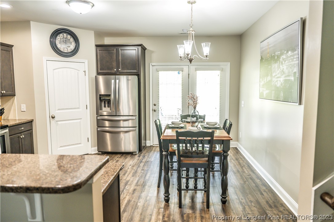 96 Eaker Drive Cameron, NC 28326 - Photo 11 of 41 a kitchen with granite countertop a refrigerator a stove a dining table and chairs with wooden floor