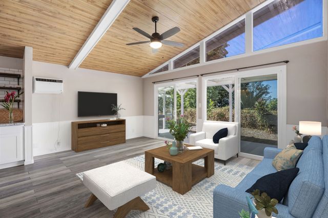 a living room with furniture a flat screen tv and a floor to ceiling window