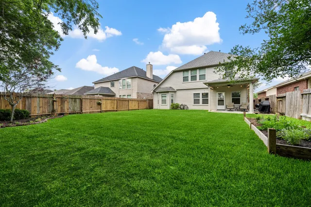 a view of a white house next to a yard with big trees