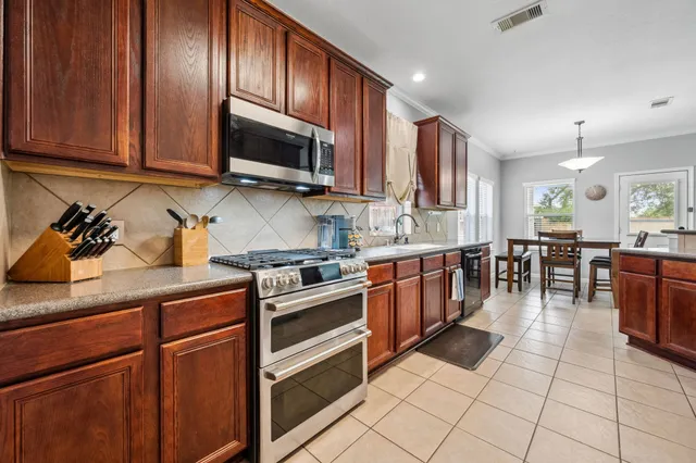 a kitchen with stainless steel appliances granite countertop wooden cabinets a stove top oven a sink and dishwasher
