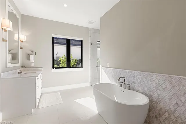 a spacious bathroom with a double vanity sink a mirror and a bathtub