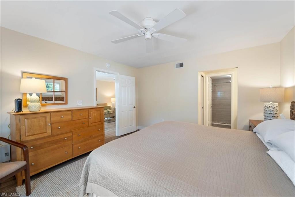 3012 Sandpiper Bay Circle, Unit D101 Naples, FL 34112 - Photo 11 of 27 a bedroom with a bed and a chandelier