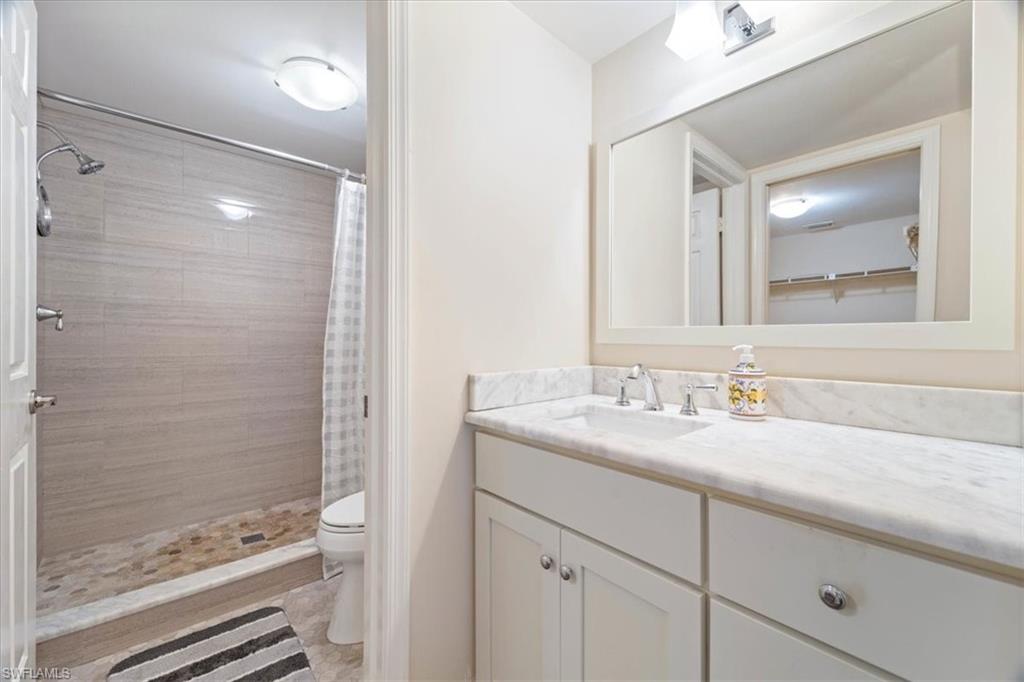 3012 Sandpiper Bay Circle, Unit D101 Naples, FL 34112 - Photo 12 of 27 a bathroom with a granite countertop sink mirror and shower