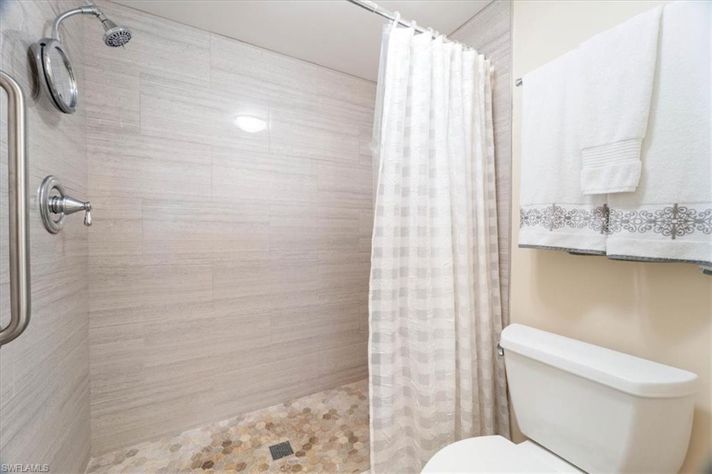 3012 Sandpiper Bay Circle, Unit D101 Naples, FL 34112 - Photo 14 of 27 a white toilet sitting next to a shower curtain