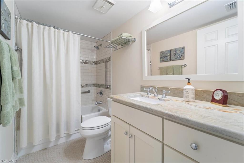 3012 Sandpiper Bay Circle, Unit D101 Naples, FL 34112 - Photo 17 of 27 a bathroom with a granite countertop sink toilet a mirror and shower curtain
