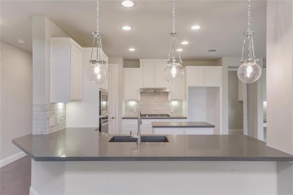 a large kitchen with kitchen island a large counter top and stainless steel appliances
