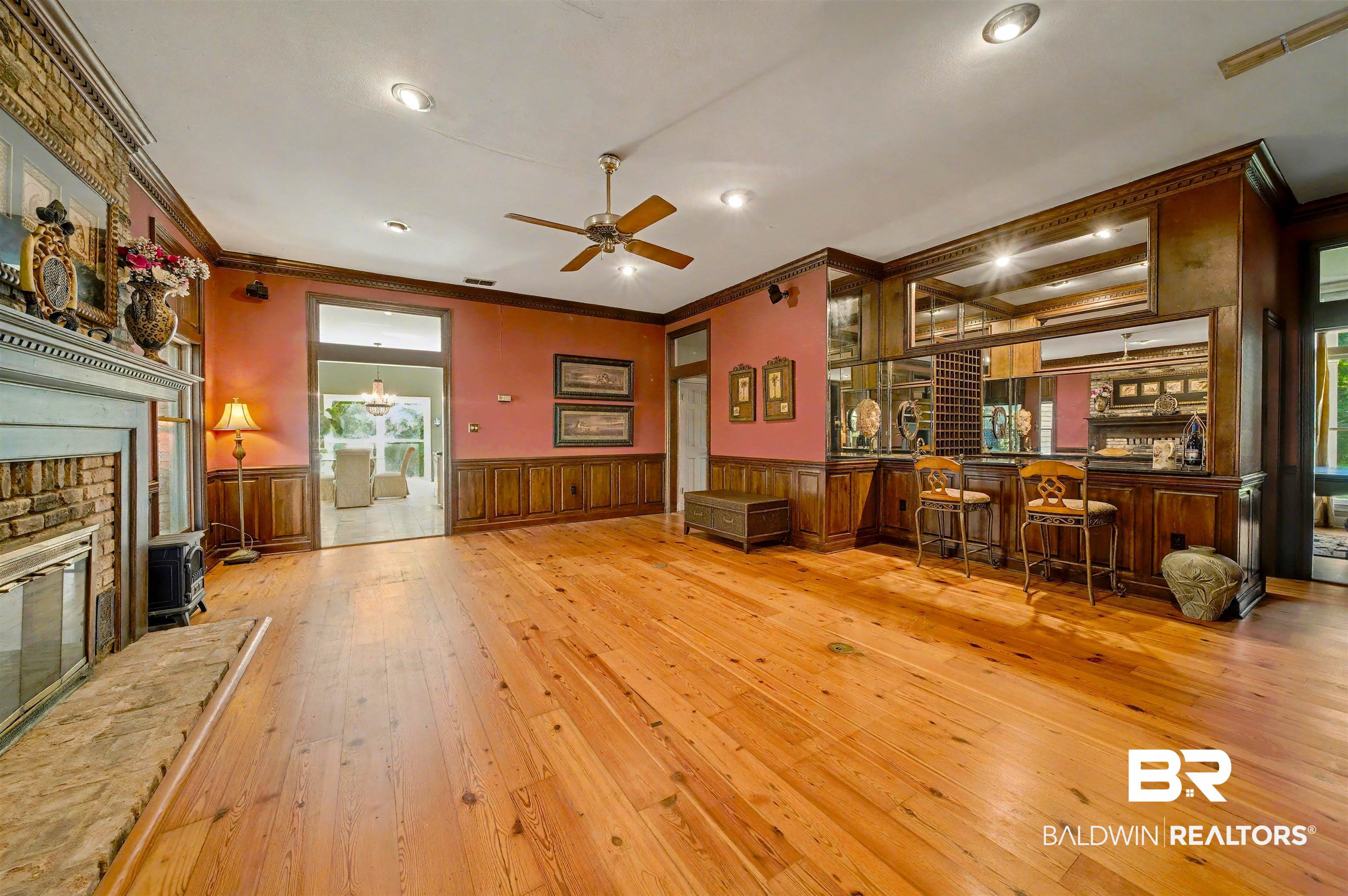 15810 County Road 73 Foley, AL 36535 - Photo 45 of 56 Unfurnished living room with crown molding, light wood finished floors, a wainscoted wall, bar, and a glass covered fireplace