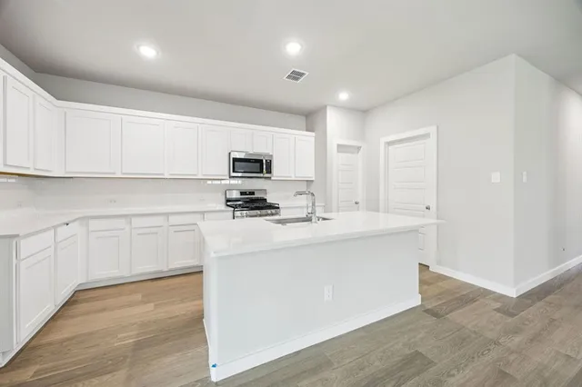 a kitchen with kitchen island a sink stainless steel appliances and cabinets