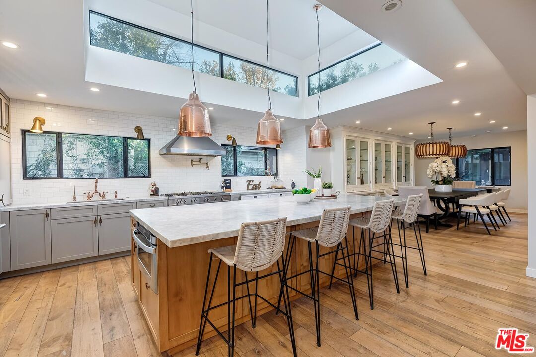 5401 Ostrom Avenue Encino, CA 91316 - Photo 13 of 73 a kitchen with stainless steel appliances a table chairs refrigerator and cabinets