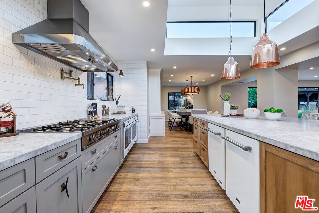 5401 Ostrom Avenue Encino, CA 91316 - Photo 15 of 73 a large kitchen with stainless steel appliances a stove a sink dishwasher and cabinets with wooden floor