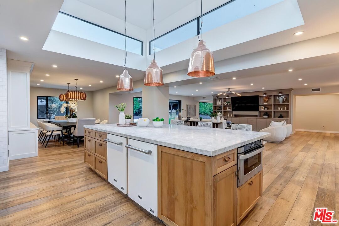 5401 Ostrom Avenue Encino, CA 91316 - Photo 16 of 73 a kitchen with stainless steel appliances granite countertop a kitchen island a stove a sink a dining table and chairs with wooden floor