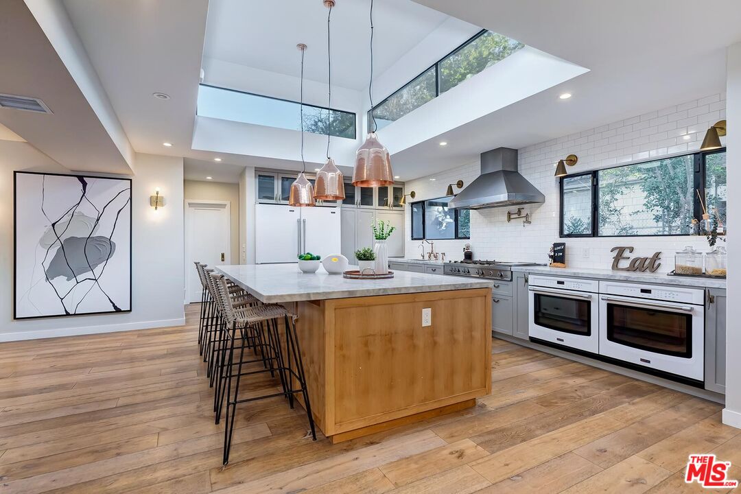 5401 Ostrom Avenue Encino, CA 91316 - Photo 18 of 73 a kitchen with stainless steel appliances granite countertop a kitchen island a stove and a wooden floors