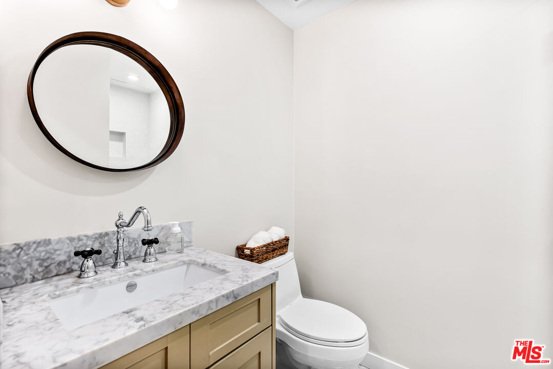 5401 Ostrom Avenue Encino, CA 91316 - Photo 48 of 73 a bathroom with a granite countertop toilet a sink and a mirror