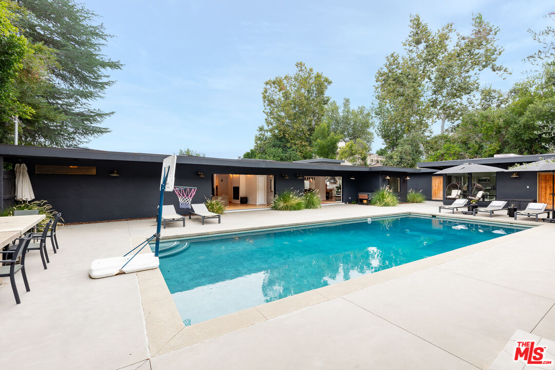5401 Ostrom Avenue Encino, CA 91316 - Photo 68 of 73 a view of a swimming pool with a table and chairs under an umbrella
