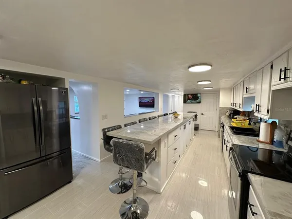 a kitchen with stainless steel appliances a stove a sink dishwasher a refrigerator with white cabinets and wooden floor