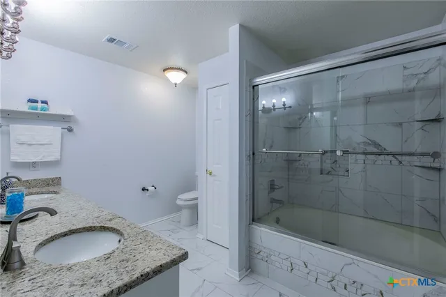 a bathroom with a granite countertop sink a toilet and bathtub