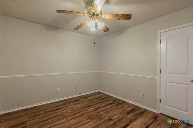 a view of a room with wooden floor and a ceiling fan