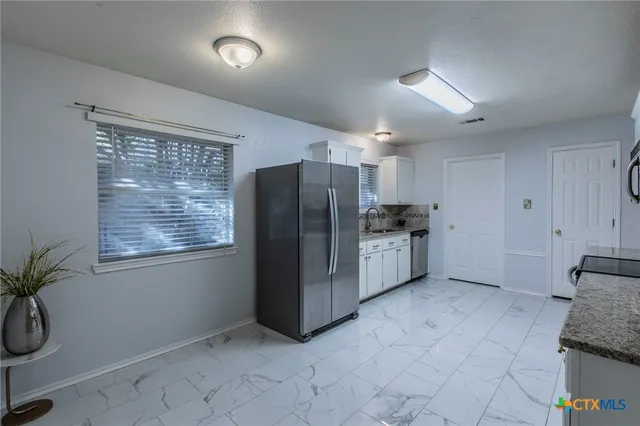 a kitchen with stainless steel appliances granite countertop a refrigerator and a sink