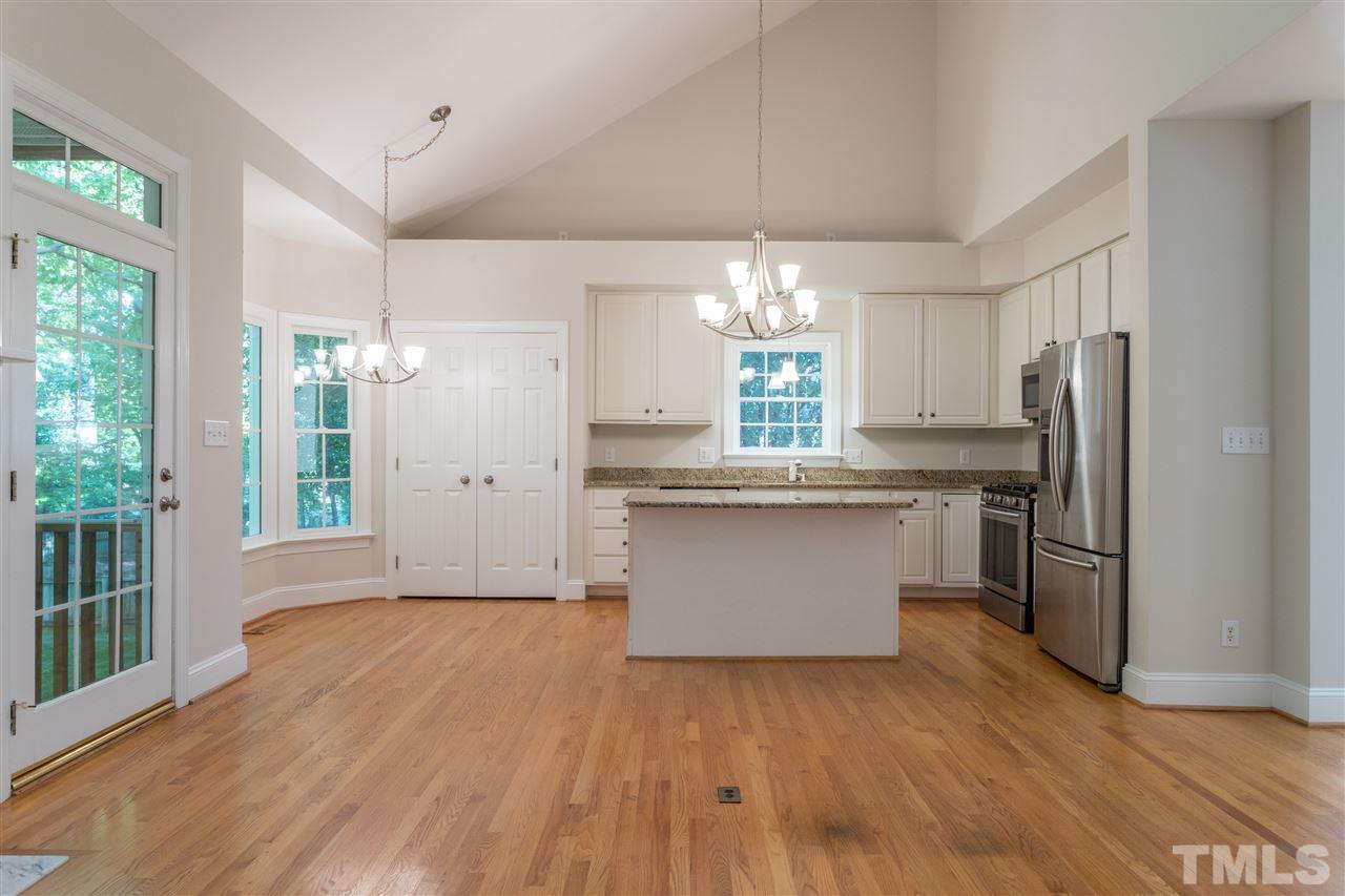 3305 Glade Spring Court Raleigh, NC 27612 - Photo 11 of 20 a large kitchen with stainless steel appliances a large counter top a refrigerator and a chandelier