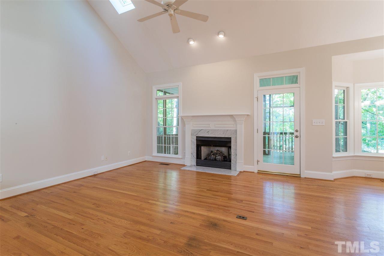 3305 Glade Spring Court Raleigh, NC 27612 - Photo 13 of 20 an empty room with wooden floor fireplace and windows