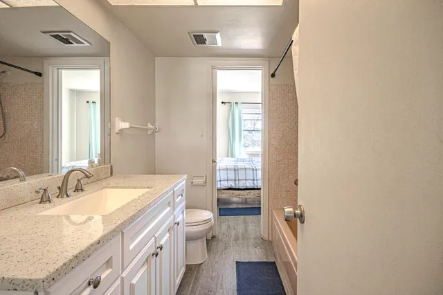 a bathroom with a granite countertop sink a toilet and a large mirror