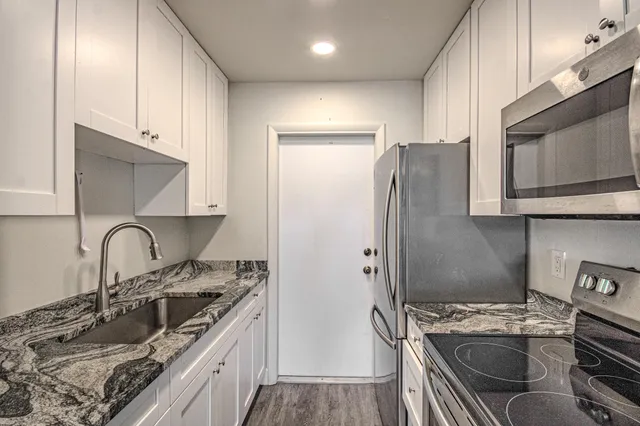 a kitchen with granite countertop a sink stove and refrigerator