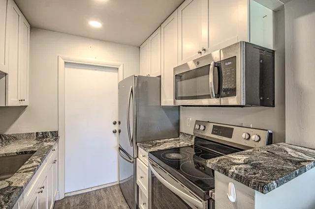 a kitchen with stainless steel appliances granite countertop a stove a refrigerator and a microwave