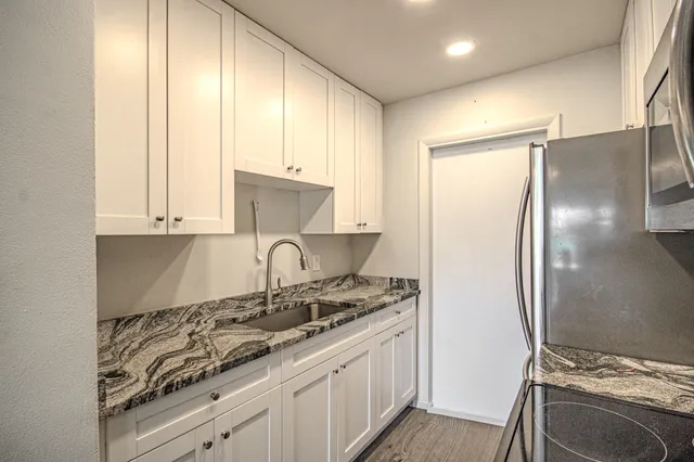 a kitchen with kitchen island granite countertop a sink stove and refrigerator