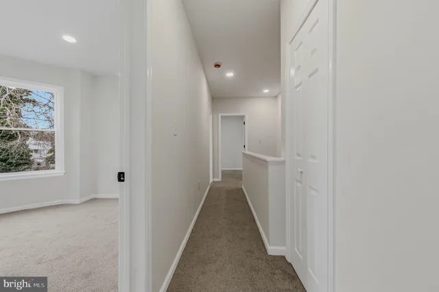 a view of a hallway with wooden floor and a bathroom