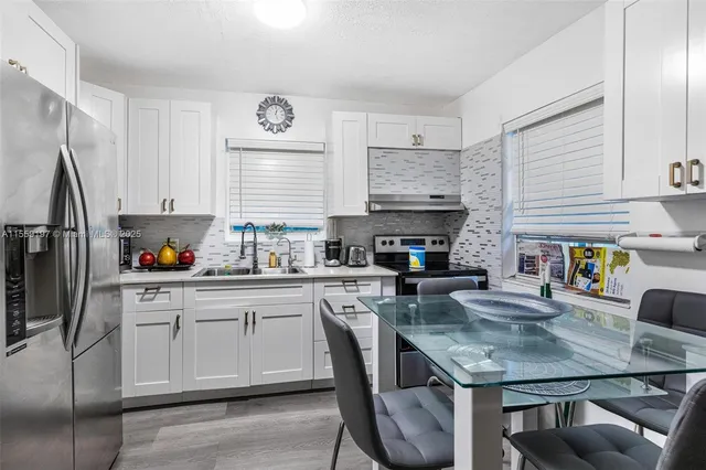 a kitchen with stainless steel appliances granite countertop a refrigerator a stove and a sink with wooden floor