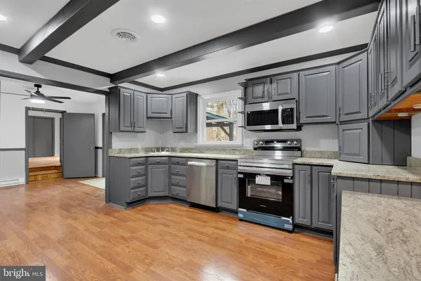 a kitchen with stainless steel appliances granite countertop a stove refrigerator sink and microwave