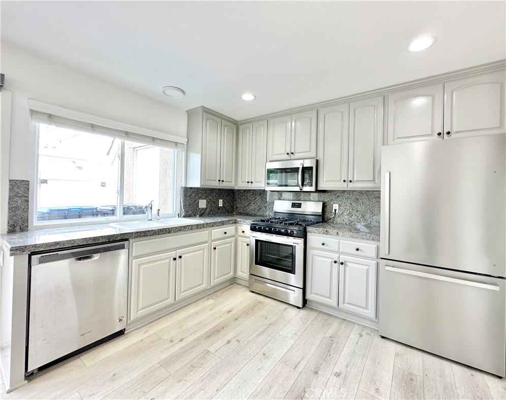 13 Greenleaf, Unit 5 Irvine, CA 92604 - Photo 11 of 30 a kitchen with white cabinets stainless steel appliances a sink and a window