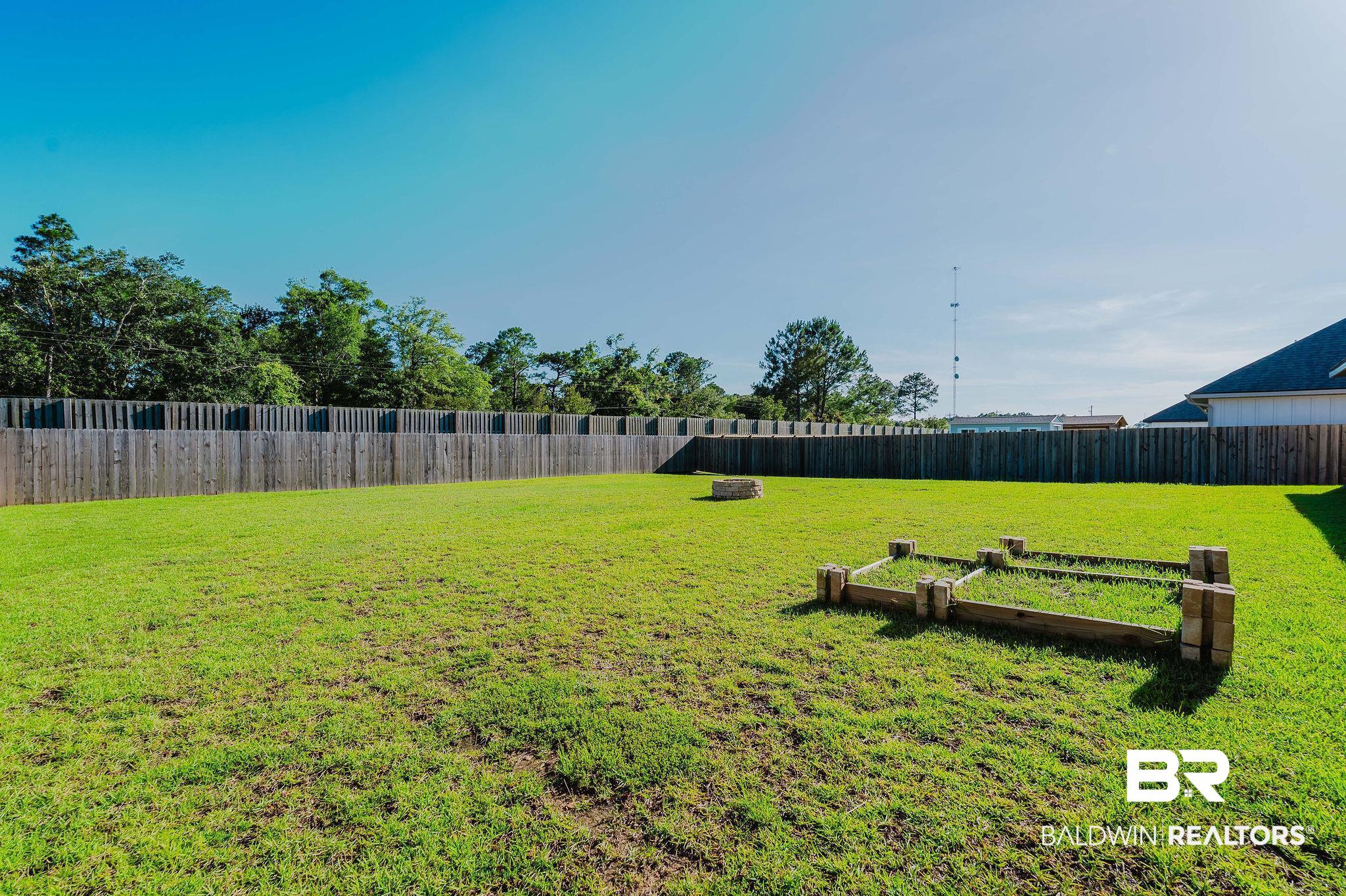 7872 Calverton Street Foley, AL 36535 - Photo 57 of 76 Expansive backyard featuring a lush green lawn, full privacy fencing, and two raised garden beds