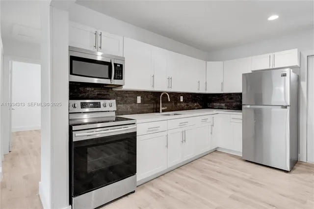 a kitchen with cabinets stainless steel appliances and wooden floor