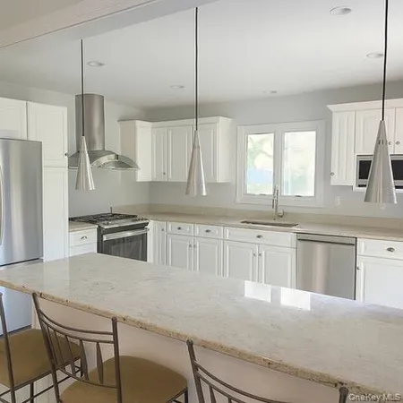 a kitchen with stainless steel appliances granite countertop a sink a stove a refrigerator a center island and cabinets