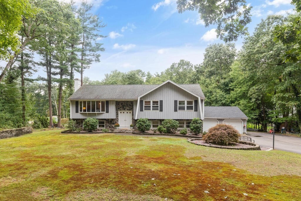 a front view of a house with a garden and trees