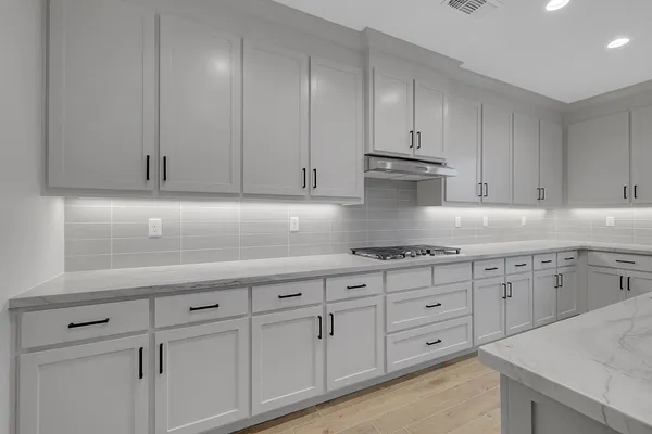 a kitchen with granite countertop white cabinets and stainless steel appliances