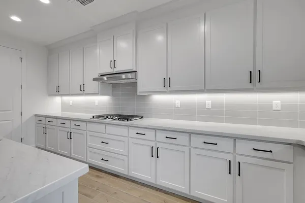 a kitchen with granite countertop white cabinets and stainless steel appliances