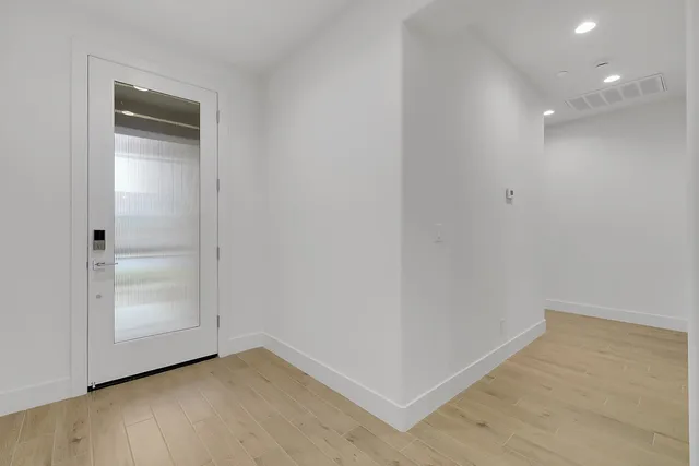 a view of an empty room with closet and wooden floor