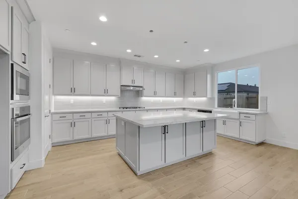 a kitchen with granite countertop white cabinets and stainless steel appliances