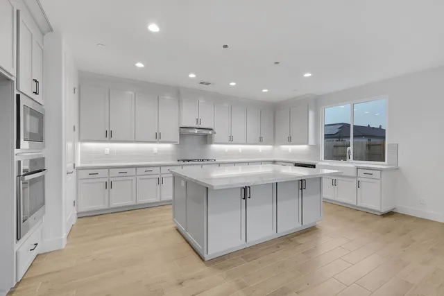 a kitchen with granite countertop white cabinets and stainless steel appliances