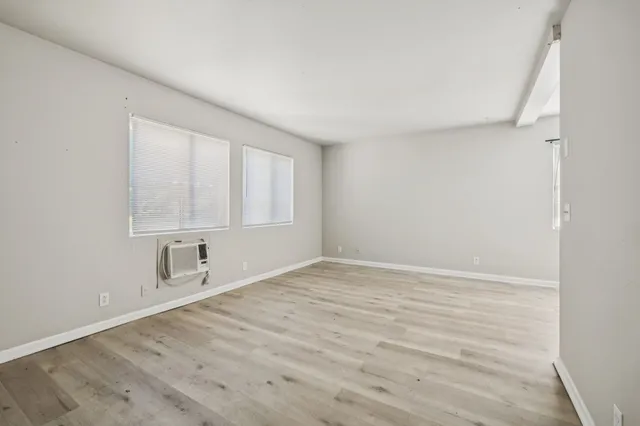 a view of an empty room with wooden floor and a window
