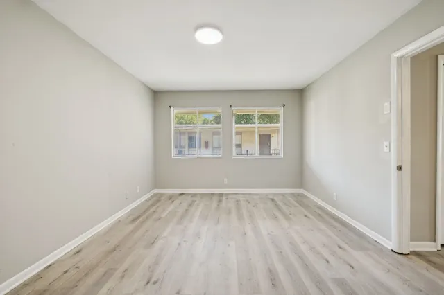 an empty room with wooden floor and windows