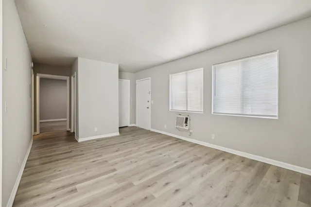 a view of an empty room with wooden floor and a window