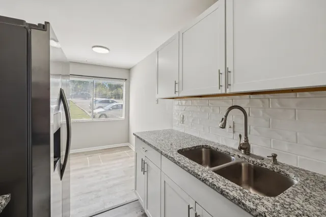 a kitchen with stainless steel appliances granite countertop a sink a refrigerator and cabinets