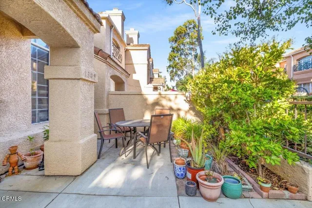 a view of a patio with table and chairs potted plants and large tree