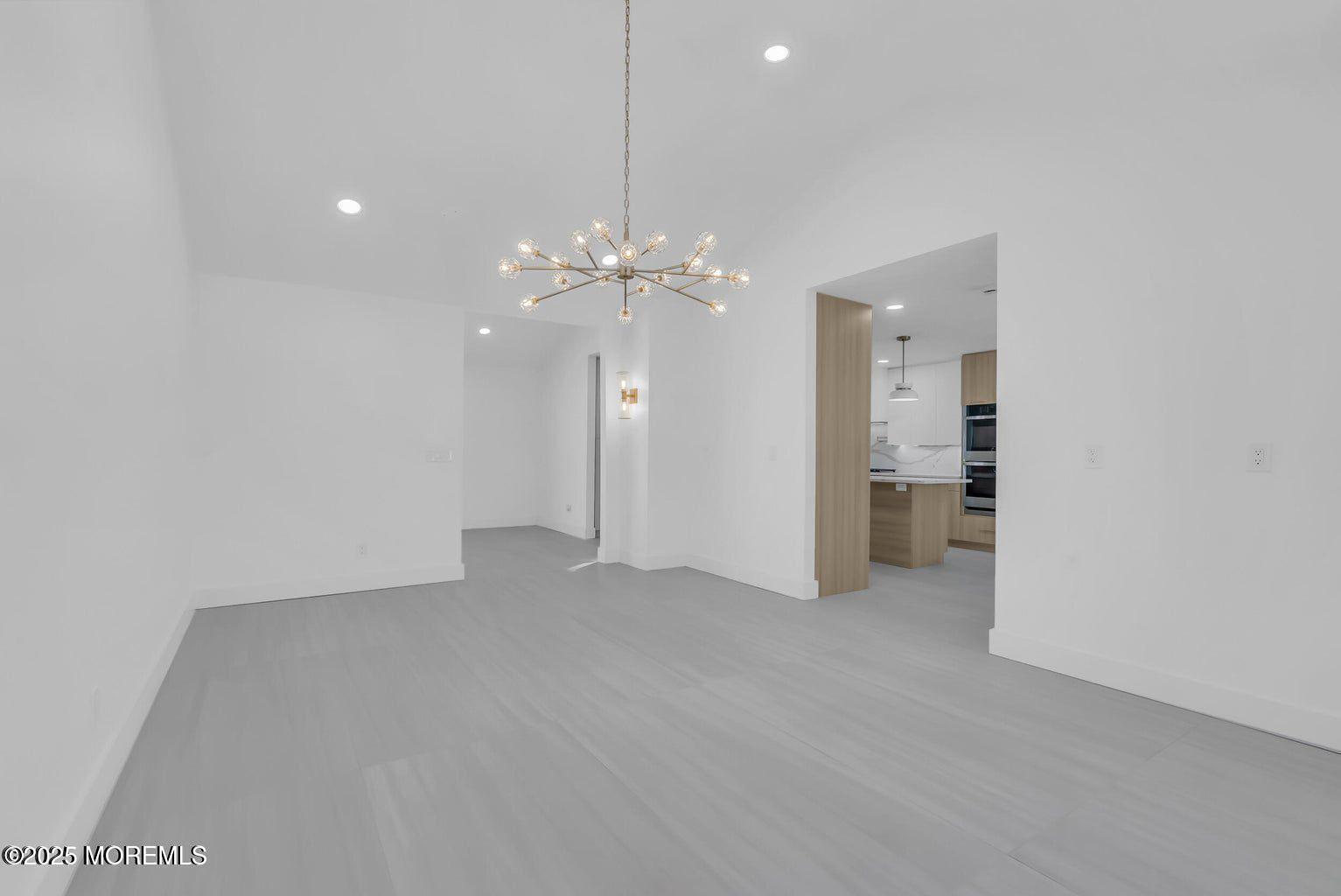 1 Robin Drive Oakhurst, NJ 07755 - Photo 7 of 42 an empty room with chandelier fan and kitchen view